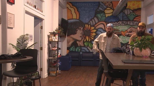 Two people at Unity Recovery, where one wall is covered by a colorful mural 