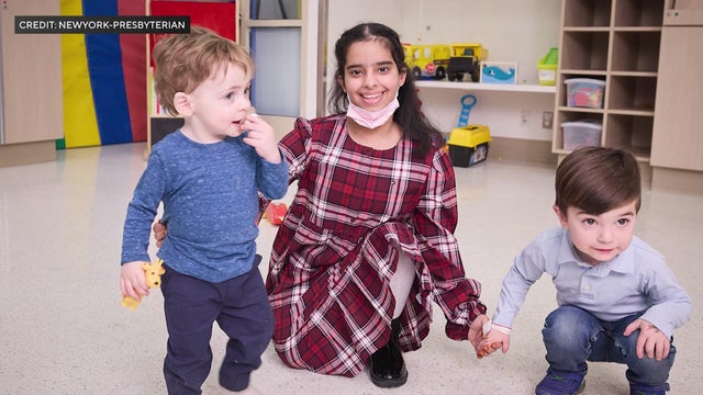An 11-year-old girl holds the hands of two toddler boys 