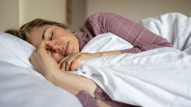 Mature woman suffering from menopause symptoms while lying in bed 
