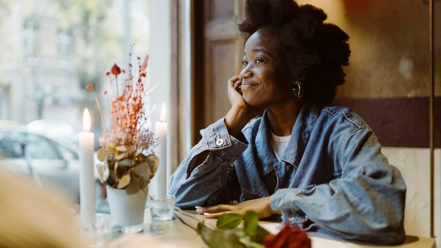 Smiling romantic woman staring at boyfriend during date at bar 