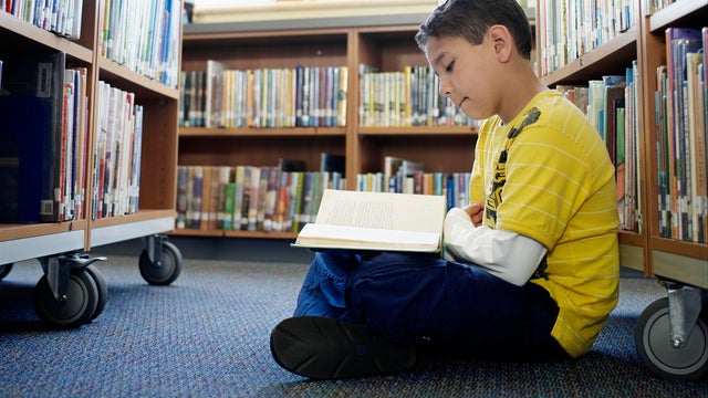 Boy sitting in aisle of library 